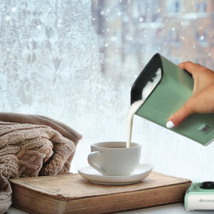 Female hand pouring frothed milk into coffee